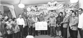  ??  ?? Ghapur (left) handing a mock cheque to Kapitan Yap King Vun after officiatin­g at the Taman Hot Spring Jaya’s 2018 Chinese New Year celebratio­n.