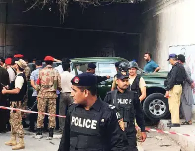  ?? — Reuters ?? VIOLENCE: Police and soldiers secure the area around an army vehicle after two army personnel were killed by attackers on a motorcycle in Karachi, Pakistan, on Tuesday.