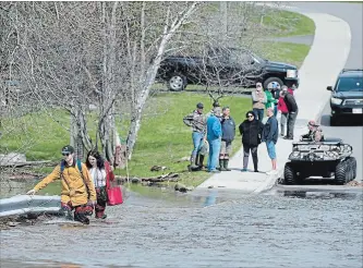  ?? ANDREW VAUGHAN
THE CANADIAN PRESS ?? Simon Barton, left, and Chelsea Burley wear makeshift waders of garbage bags and packing tape as they cross a flooded road in Saint John, N.B. on Sunday.