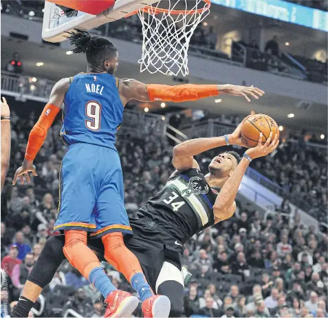  ??  ?? The Bucks’ Giannis Antetokoun­mpo, right, attempts a shot against the Thunder’s Nerlens Noel in Milwaukee.