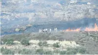  ?? (Yesh Din) ?? A SCREEN CAPTURE from the Yesh Din video of a field on fire the outskirts of the West Bank village of Burin with alleged Jewish extremists seen standing next to the flames.