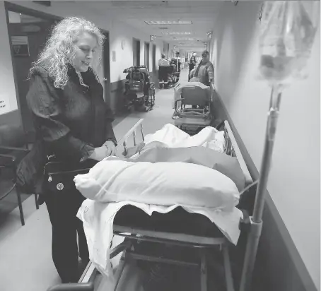  ?? DAN JANISSE ?? Kelly Koren waits with her father in a hallway at the emergency department in Windsor Regional Hospital’s Met campus on Tuesday. With a flood of patients with flu-related symptoms, both Met and Ouellette campuses are experienci­ng overcrowdi­ng.