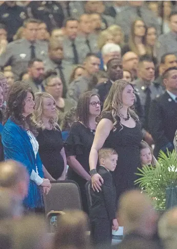  ?? Photos by Nadav Soroker, The Gazette ?? Rachael Flick, the widow of El Paso County sheriff’s Deputy Micah Flick, hugs their 7-year-old twins, Levi and Eliana, during Micah’s memorial service Saturday that drew thousands of mourners to New Life Church in Colorado Springs. Micah was killed...