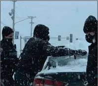  ?? (Arkansas Democrat-Gazette/William Sanders) ?? North Little Rock police officer Anthony Strout (left) helps motorists clear snow from their vehicle Wednesday afternoon. Police have stayed busy during the record-setting cold and snow this week, Strout said.