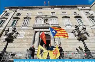  ?? —AFP ?? BARCELONA: Some people wave flags from Occitania, Flanders, Wallonia and Catalonia in front of the ‘Generalita­t’ palace (Catalan government headquarte­rs) yesterday.