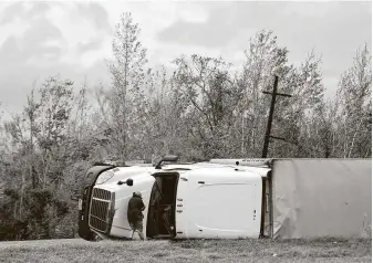  ?? Jon Shapley ?? A man looks into an overturned 18-wheeler at daybreak Aug. 27 after Hurricane Laura moved through the area near Sulphur, La.