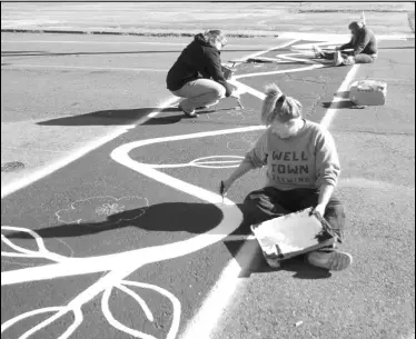  ?? Photos by Alexis Meeks ?? Above and Below: Members of the Ouachita River Art Guild paint a mural on the crosswalk outside of the Malvern-Hot Spring County Library Tuesday.