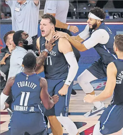  ?? FOTO: AP ?? Doncic agasajado por sus compañeros, instantes después de haber logrado el triple que dio la victoria a los Dallas Mavericks