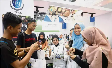  ??  ?? Taste of the future: Quest Internatio­nal University Perak School of Business and Management lecturer Asma Amirah Ahmad (centre) offering fair visitors the galaxy lemonade mocktail at the university’s booth at the Star Education Fair 2019 at the KL Convention Centre.