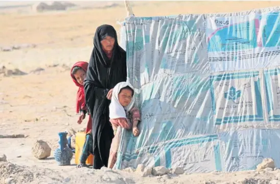  ??  ?? DESPERATE TIMES: An internally displaced woman stands with her daughters at a makeshift tent in Mazar-i-Sharif, Afghanista­n.