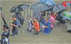  ??  ?? MUMBAI: People walk along a flooded street during heavy rain showers in Mumbai.