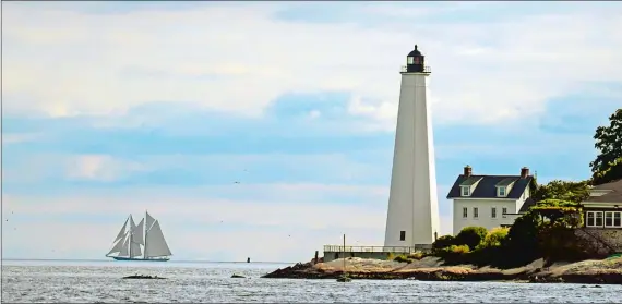  ?? SEAN D. ELLIOT/THE DAY ?? The schooner Columbia sails in the distance Friday with New London Harbor Light in the foreground. The Columbia is in town for the Connecticu­t Maritime Heritage Festival.