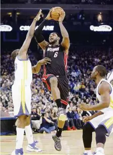  ?? AP ?? A milestone: Miami Heat’s LeBron James being marked by Golden State Warriors’ Draymond Green in their match in Oakland on Wednesday. James powered his team to a 92-75 win en route to becoming the youngest player to score 20,000 points in NBA history. —