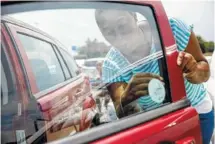  ?? STAFF FILE PHOTO BY DOUG STRICKLAND ?? Latoya Percy puts a “Look before you lock” sticker in her window after a hot car awareness news conference in 2016 in Chattanoog­a. The campaign sought to raise awareness of the dangers of leaving children and pets inside hot cars.