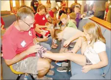  ?? FILE PHOTO ?? Jim Hendricks, a member of Farmington United Methodist Church, helps this girl find a pair of free tennis shoes at the 2018 Back 2 School Bonanza sponsored by the church, along with volunteers from many others in the community. This year’s event will be a drive-thru service only to offer free shoes and free pizza for the family because of covid-19 concerns.