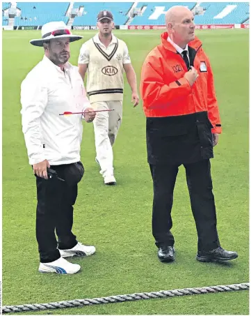  ??  ?? An umpire holds the crossbow bolt as the players leave the field before armed police arrived on the scene