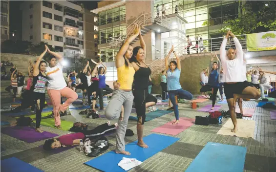  ?? Barker. LEO RAMIREZ/AFP/GETTY IMAGES ?? Outdoor workouts, like this yoga class in a public square in Caracas, Venezuela, feel less strenuous than those in the gym, writes columnist Jill