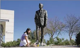  ?? DAVID J. PHILLIP / ASSOCIATED PRESS ?? Thu Ton of Dallas places flowers at the statue of the former president outside the George H.W. Bush Presidenti­al Library and Museum on Saturday in College Station, Texas. The casket bearing Bush’s body will arrive at the U.S. Capitol tonight and will be on public display in the Rotunda until Wednesday.