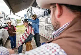  ?? Jon Shapley photos/ Houston Chronicle ?? Top left: Justin Davis, a roping competitor, holds his daughter, Shyla. Top right: Cody Snow prepares to wash his horses during down time at Rodeo Village. Above: Randall Carlisle gets his hair cut by Eugene King, as Bill Eppley, left, and Ryan Petree watch.