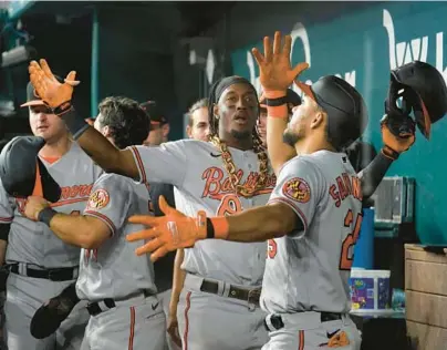  ?? TONY GUTIERREZ/AP ?? Orioles shortstop Jorge Mateo, center, and left fielder Anthony Santander, right, celebrate in the dugout after Mateo hit a two-run home run in the ninth inning of Tuesday night’s 8-2 win over the Rangers.