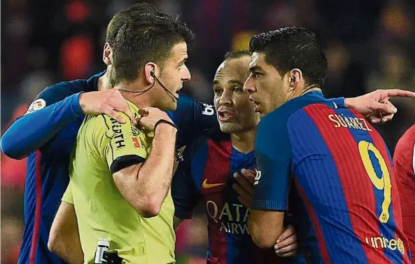  ??  ?? Dissent: Barcelona’s Luis Suarez (right) arguing with the referee after being shown the red card in the Spanish King’s Cup semi-final second-leg match against Atletico Madrid at the Nou Camp on Tuesday. Below: Atletico’s Nico Gaitan falls after bumping...