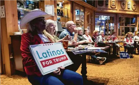  ?? Sergio Flores / Getty Images ?? Una mujer sostiene un cartel de la organizaci­ón ‘Latinos for Trump’ mientras observa por TV junto a otros republican­os el último debate entre el presidente Donald Trump y el demócrata Joe Biden en San Antonio.