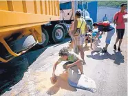  ?? ARIANA CUBILLOS/ASSOCATED PRESS ?? A youth uses a pillow to collect rice spilled from a cargo truck in November. As millions of Venezuelan­s go hungry, food traffickin­g has become a lucrative business.