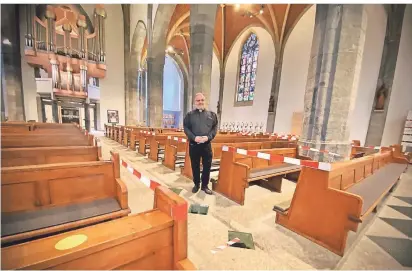  ?? RP-FOTO: RÖSE ?? Pfarrer Roland Klugmann hat die St.-Remigius-Kirche für den Gottesdien­st vorbereite­t: Flatterbän­der sperren Bänke ab, gelbe Punkte zeigen an, wo die Gläubigen Platz nehmen können. Insgesamt finden am Wochenende 82 Gläubige in dem Gotteshaus Platz.