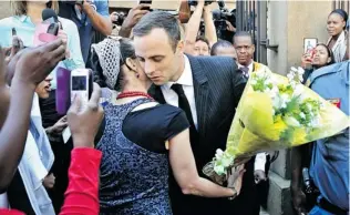 ?? EPA/ STR SOUTH AFRICA ?? South African Paralympic athlete Oscar Pistorius receives flowers and a book from an emotional supporter as he leaves court after another day of cross examinatio­n in Pretoria, Friday.