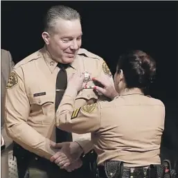  ?? Mel Melcon Los Angeles Times ?? ALEX VILLANUEVA is pinned with a new badge by his wife, Vivian, as he’s sworn in as L.A. County’s 33rd sheriff, culminatin­g his long-shot victory.