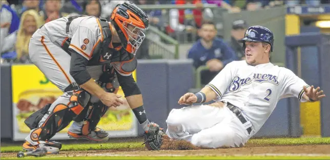  ??  ?? Brewers second baseman Scooter Gennett is tagged out at home by San Francisco Giants catcher Buster Posey in the fourth inning of Milwaukee’s season-opening loss on Monday at a sold-out Miller Park.