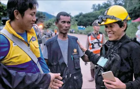  ?? Linh Pham/Getty Images ?? Rescue workers along the main road lead to Tham Luang Nang Non cave Sunday as the first two ambulances carrying two boys pass by in Chiang Rai, Thailand.