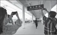  ?? WU WEIHONG / FOR CHINA DAILY ?? Visitors take pictures of the station board at Zhanjiangx­i railway station in Zhanjiang, Guangdong province.