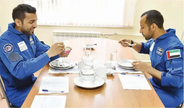  ??  ?? ↑ Emirati astronauts Hazza Al Mansouri and Sultan Al Nayadi dine together.