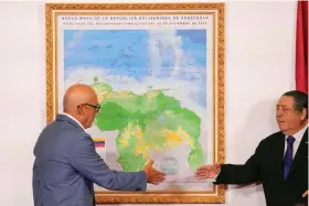  ?? (AP Photo/Matias Delacroix) ?? National Assembly President Jorge Rodriguez, left, and Chairman of the Special Commission for the Defense of Guyana Essequibo Hermann Escarra, shake hands after unveiling Venezuela’s new map that includes the Essequibo territory, a swath of land that is administer­ed and controlled by Guyana but claimed by Venezuela, in Caracas, Venezuela, Friday, Dec. 8, 2023.