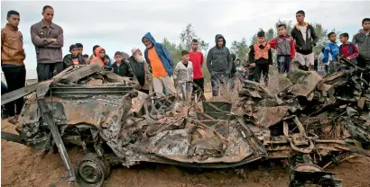  ?? AFP ?? palestinia­ns stand next to the remains of a car that was destroyed following an Israeli air strike in Khan Yunis in the southern gaza strip on Monday. —