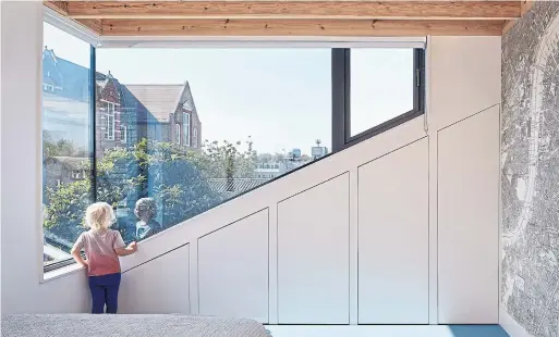  ?? ANDY STAGG PHOTOS ?? A view of the neighbourh­ood skyline through the oversized window in the third-floor loft addition, which helped create a modern home with a comfortabl­e, airy feel.