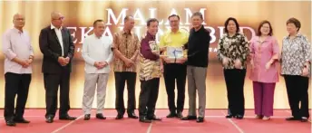  ??  ?? Bakeri (fourth right) receives a mementos from Dr Sim, witnessed by the rest of the dignitarie­s from the ministry.