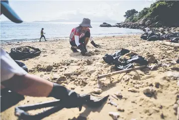  ?? — AFP photo ?? Volunteers help remove washed up palm oil from a beach on Hong Kong’s outlying Lamma Island.