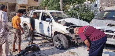  ?? Agencve France-presse ?? Syrian civilians gather around a damaged car after an explosive device wounded a man and a child in Binnish, Idlib.