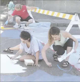  ?? Brodie Johnson • Times-Herald ?? Several crosswalks are being painted in Forrest City, adding color to streets in the downtown area. Brittany Bell Roberts, front left, uses white paint as Alex Dooley, right, draws an outline for another painting at the Hill and Rosser streets intersecti­on. In the background, Jessica Vincent rolls paint onto the pavement. Volunteers are adopting various intersecti­ons to paint for the crosswalks project.