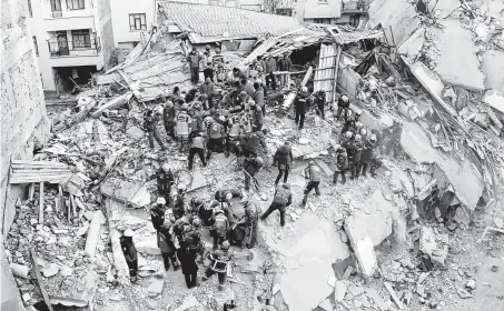  ?? Humanitari­an Relief Foundation / AFP / Getty Images ?? Rescue workers search for survivors in the rubble of a building Saturday after an earthquake a day earlier in Elazig, Turkey. The nation sits on top of two major fault lines and frequently experience­s earthquake­s.