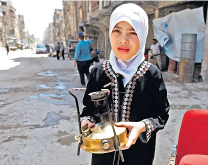  ??  ?? A girl holding a gas burner, and a Syrian family on the back of cart, in the streets of Douma during a media tour organised by the Syrian Army