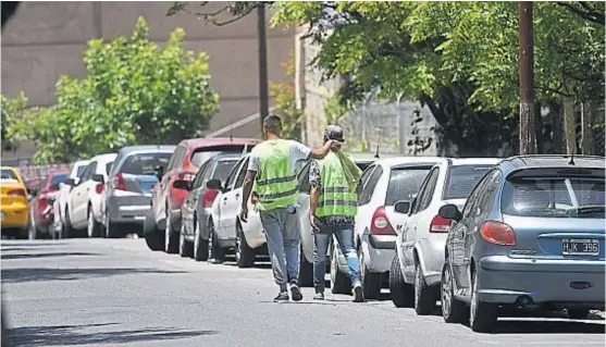  ?? (PEDRO CASTILLO) ?? Cooperativ­as. Dos "naranjitas" cuidaban ayer una larga hilera de vehículos en una de las zonas que les restituyó la Justicia.