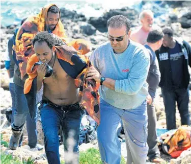  ?? NIKOLAS NANEV/ASSOCIATED PRESS ?? A Greek man helps a migrant to leave shore in the eastern Aegean island of Rhodes, Greece, on Monday. Greek authoritie­s fear that as many as 700 people died late Saturday when a boat packed with migrants capsized.