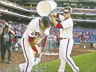  ?? GETTY ?? Cesar Hernandez gets a celebrator­y ice bucket shower after his two-out single in ninth lifts Phillies past Nationals Sunday in afternoon NL East showdown.