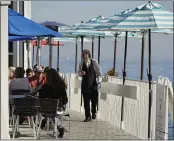  ?? ERIC RISBERG — THE ASSOCIATED PRESS FILE ?? A waiter walks past tables of people dining outdoors at Scoma’s restaurant in Sausalito.