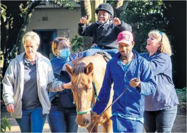  ?? ?? Bahlophe Khumalo, all smiles and riding with no hands, is supported by Les Ervine (Dayspring), Sinakho Buthelezi (physio) and Sarah Lombard, while the horse is led by a Dayspring staff member