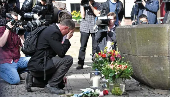  ??  ?? A man pauses to pay his respects as he brings flowers to the scene of the van attack outside the popular pub Grosser Kiepenkerl in Muenster