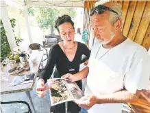  ?? See a gallery of images at
timesfreep­ress.com ?? Rick Owens shows Stephanie Everett photos while speaking to her about how the power company lopped a significan­t amount of his tree tops off to clear the way for existing power poles.